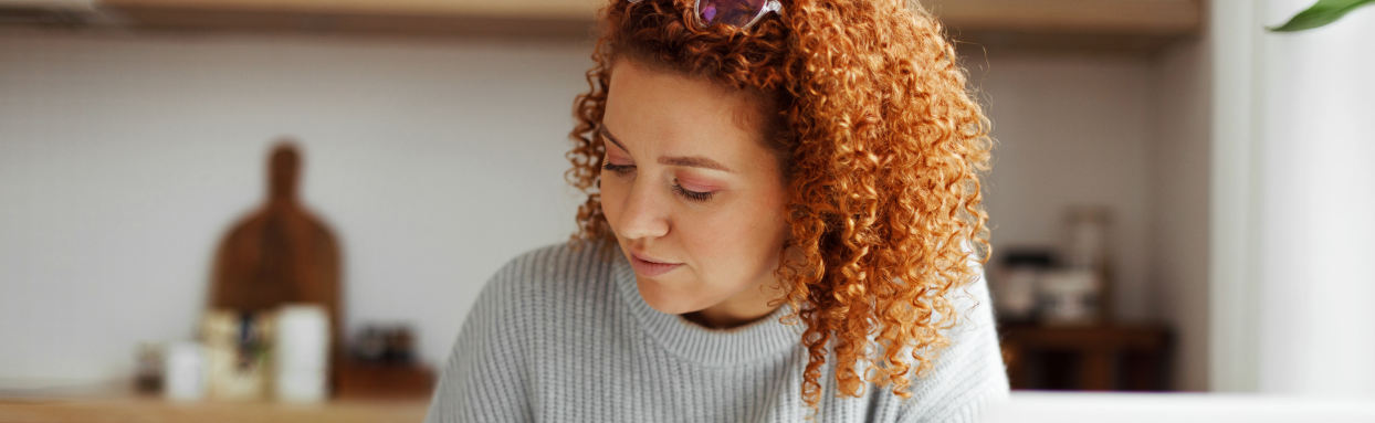 Woman with curly hair writing on her kitchen table