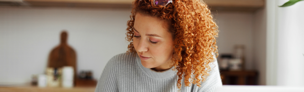 Woman with curly hair writing on her kitchen table