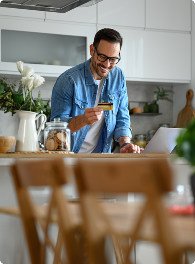 Man doing online banking happily in his kitchen