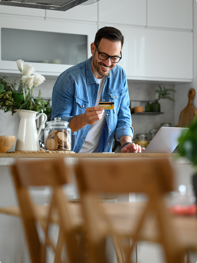 Man doing online banking happily in his kitchen