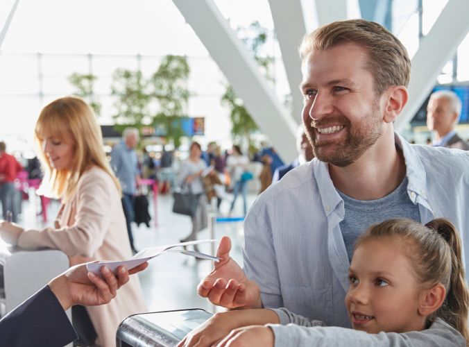 Family at airline service desk receiving boarding pass from agent