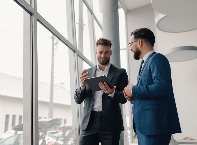 Two men talking while looking at a tablet