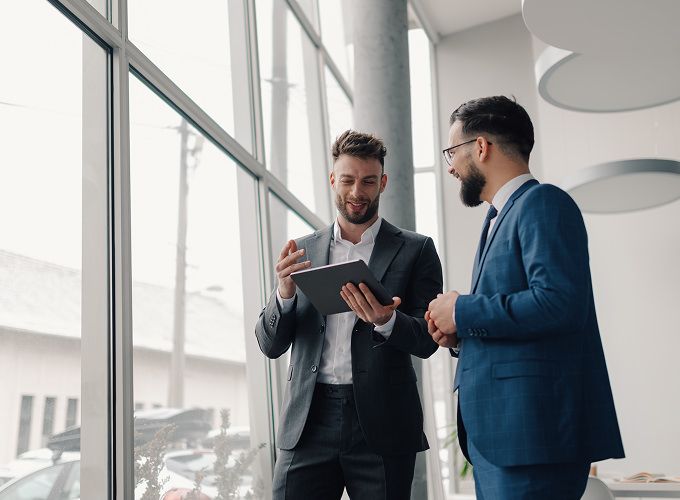 Two men talking while looking at a tablet