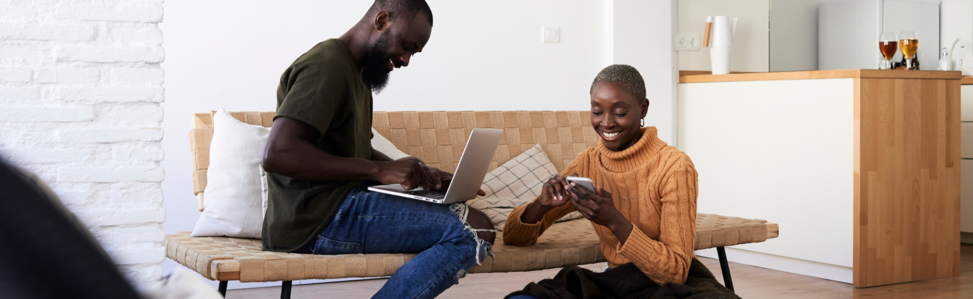 Two people sitting in a living room, a man with a laptop and a woman with a smartphone