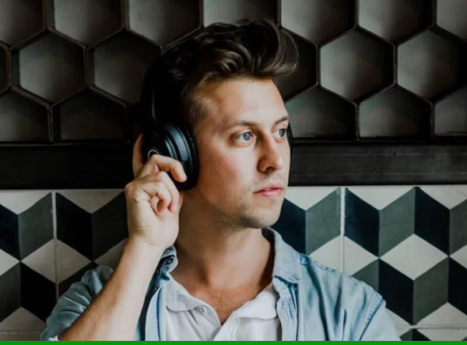 A person wearing headphones, looking contemplative, stands against a geometric-patterned wall. The tone is thoughtful, with a modern and stylish backdrop.