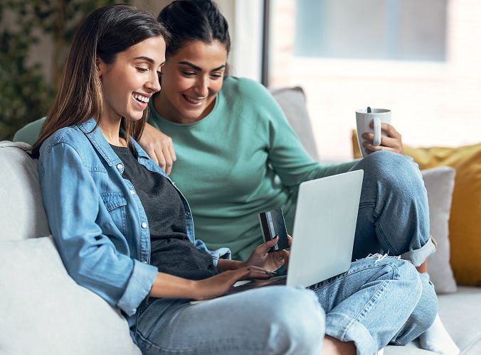 Two women shopping on a laptop