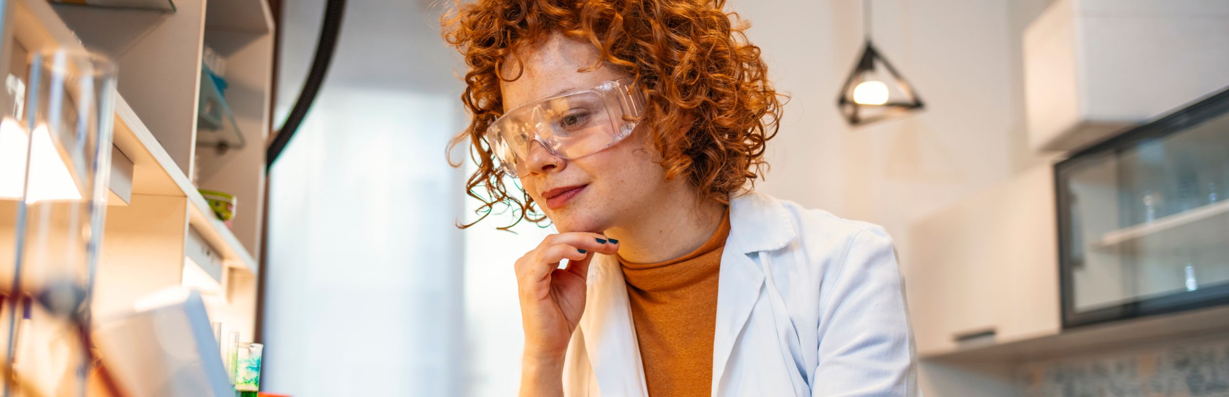 Scientist wearing safety goggles in a lab reviewing laptop