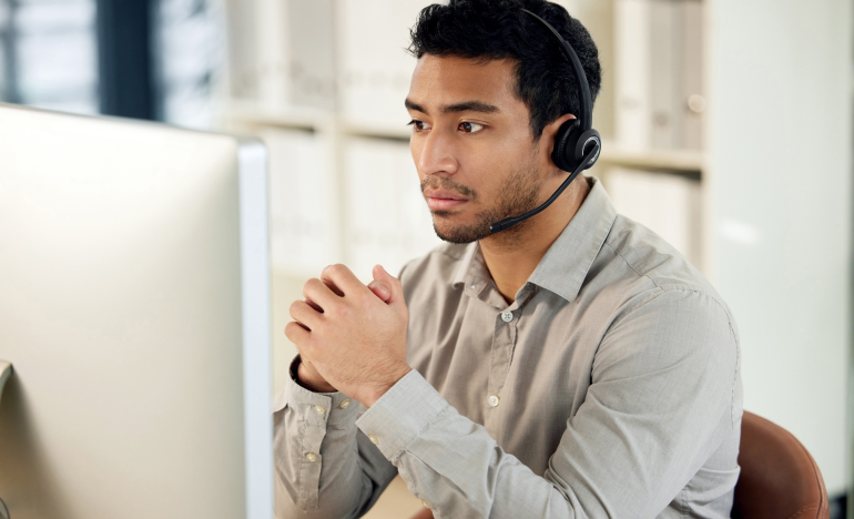 man with a phone headset looking at a monitor