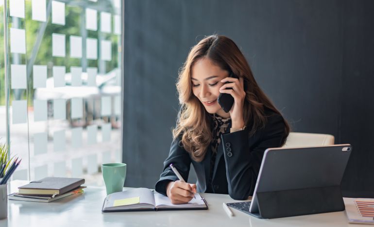 Business woman on the phone next to a laptop