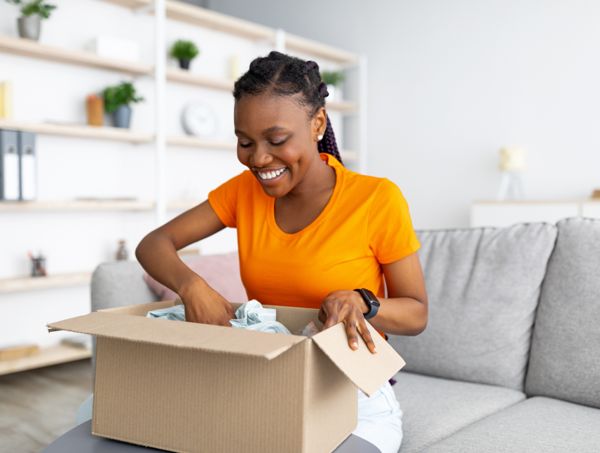 Smiling woman unpacking an online order from a cardboard box in her living room