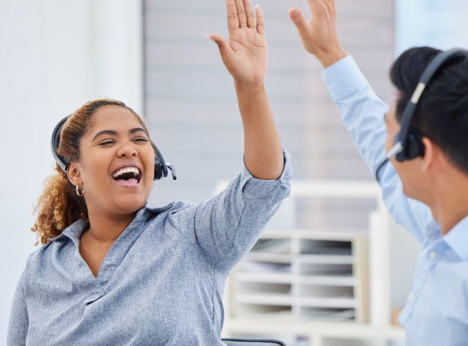 Two customer service colleagues high fiving