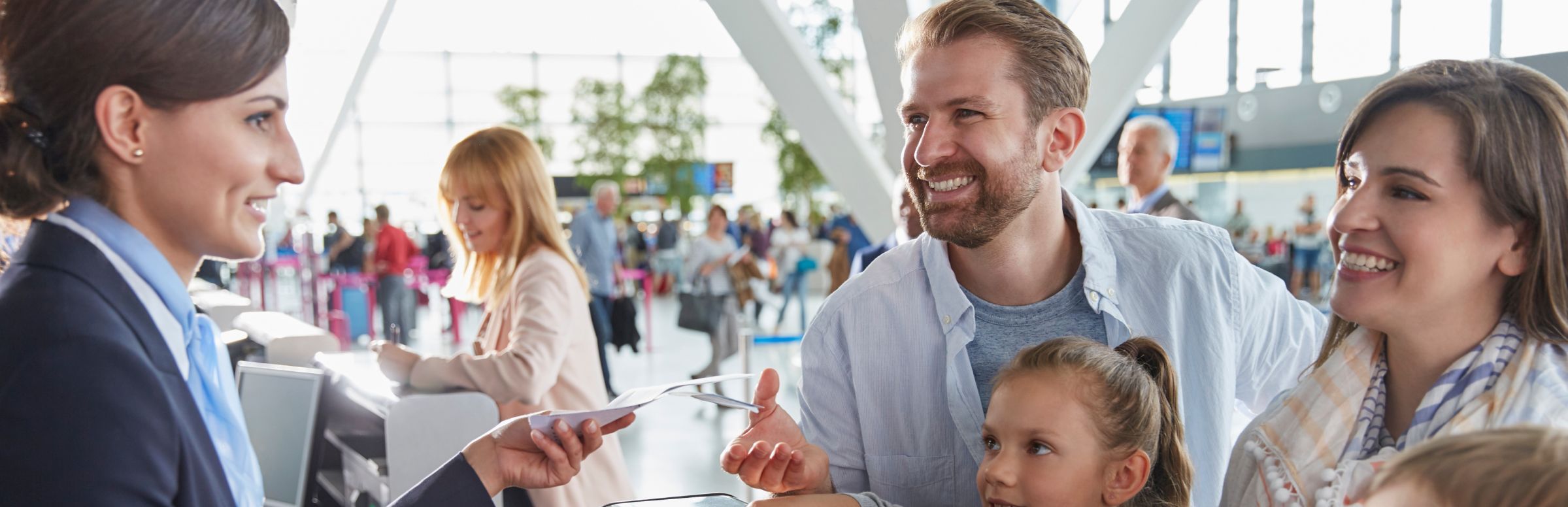 Family at airline service desk receiving boarding pass from agent