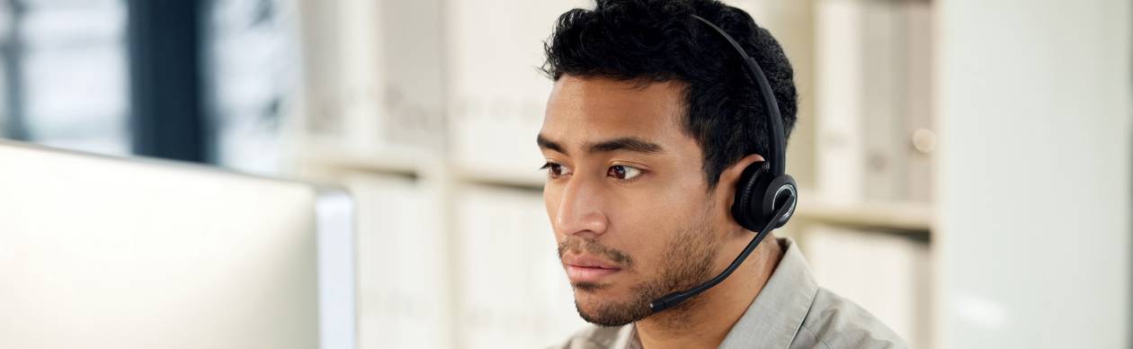 man with a phone headset looking at a monitor