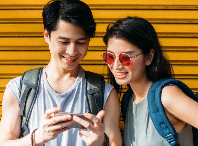 Two friends smiling and looking at a cellphone