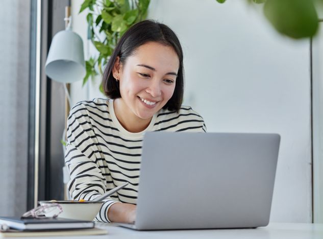 Woman in a striped shirt smiling at her laptop