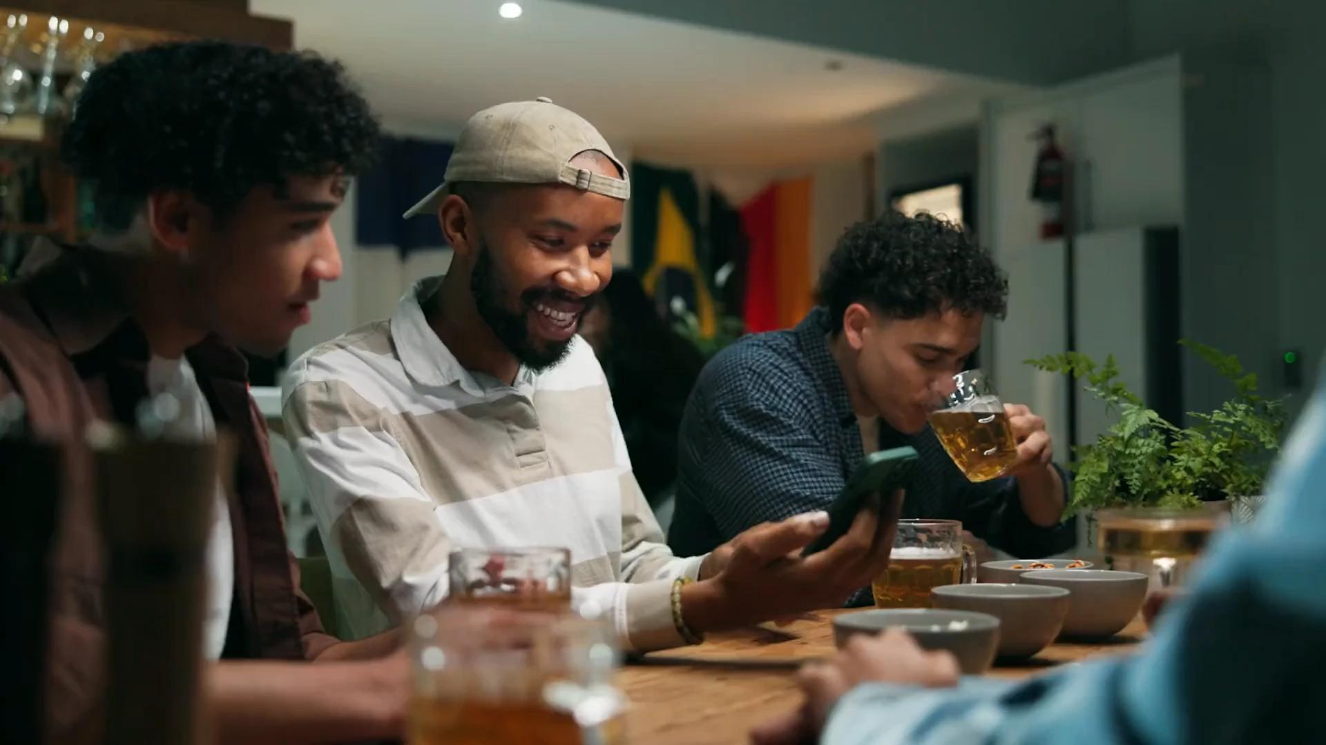 Friends around a table, one of them checking a phone