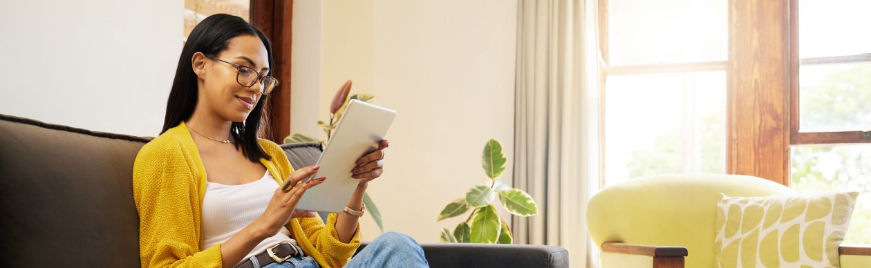 Woman relaxing on the couch in her living room looking at a tablet