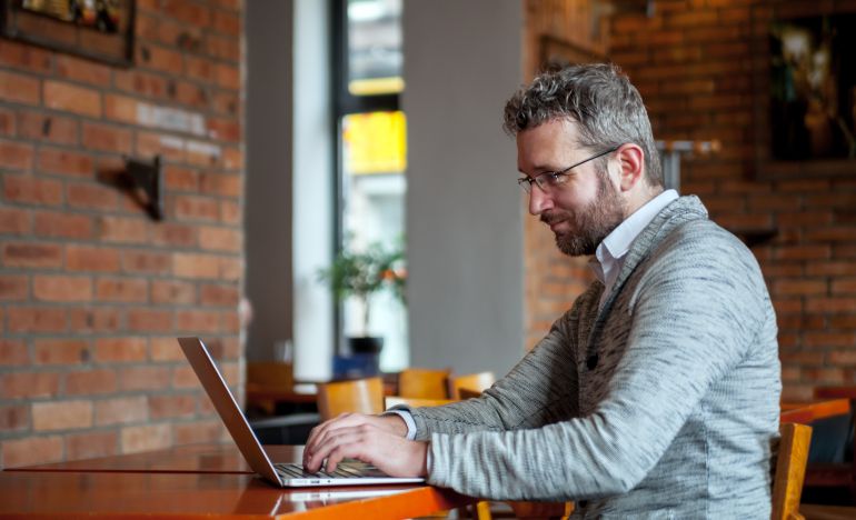 Bespectacled man working on a laptop