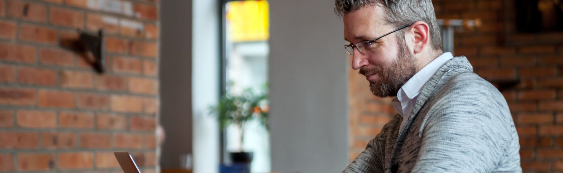 Bespectacled man working on a laptop