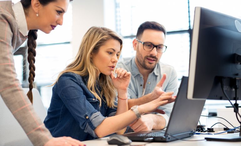 Workers crowding around computer discussing whether their customer service is ready for AI