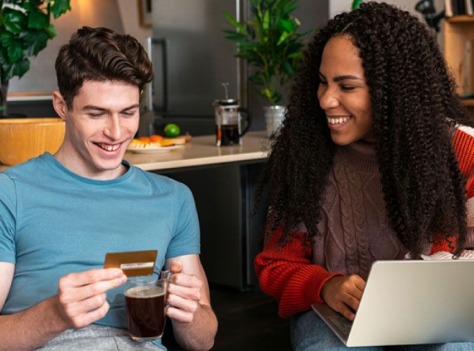 Man using credit card next to woman on laptop