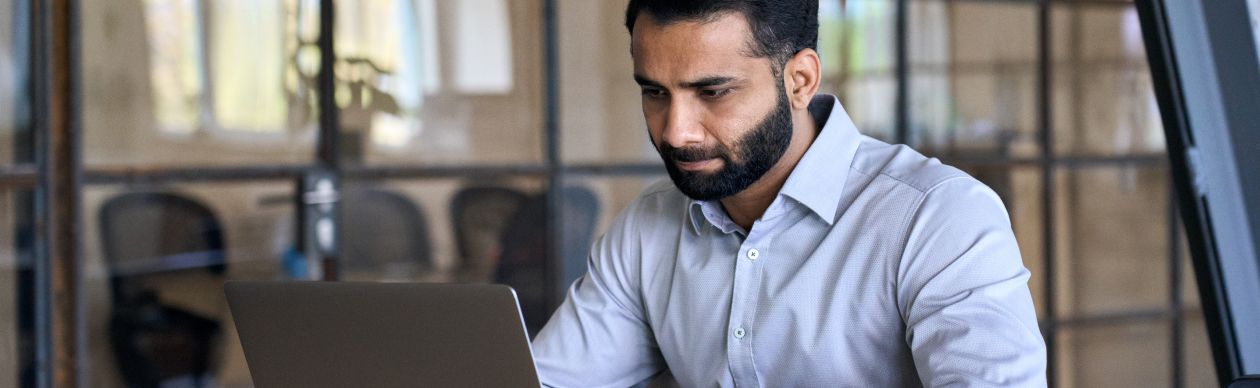 Bearded businessman staring seriously at a laptop