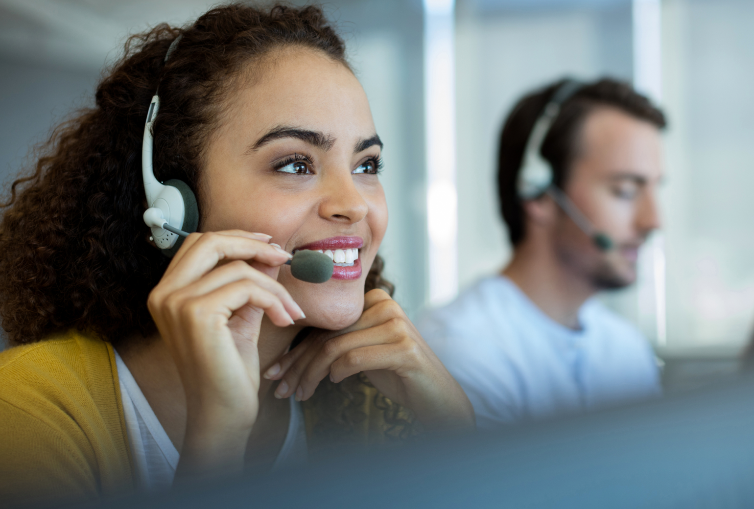 A woman smiling and talking on a phone headset