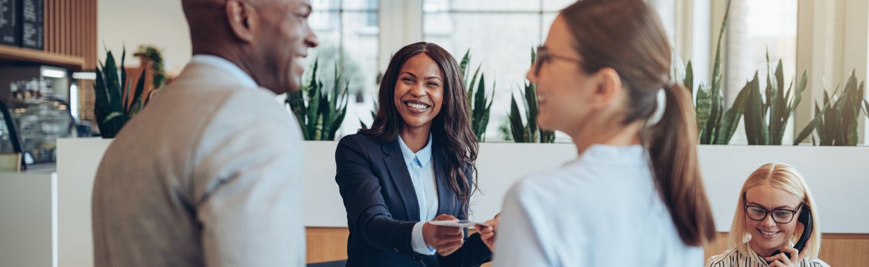 a smiling lady helping a couple check in at hotel