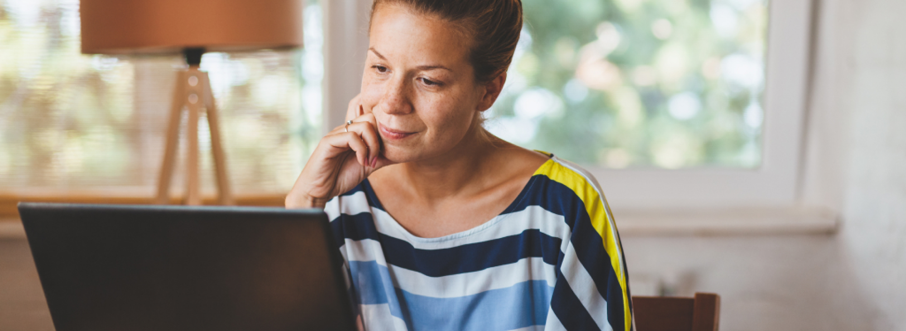 woman looking thoughtfully at laptop