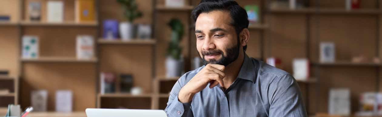 Bearded man smiling at a laptop