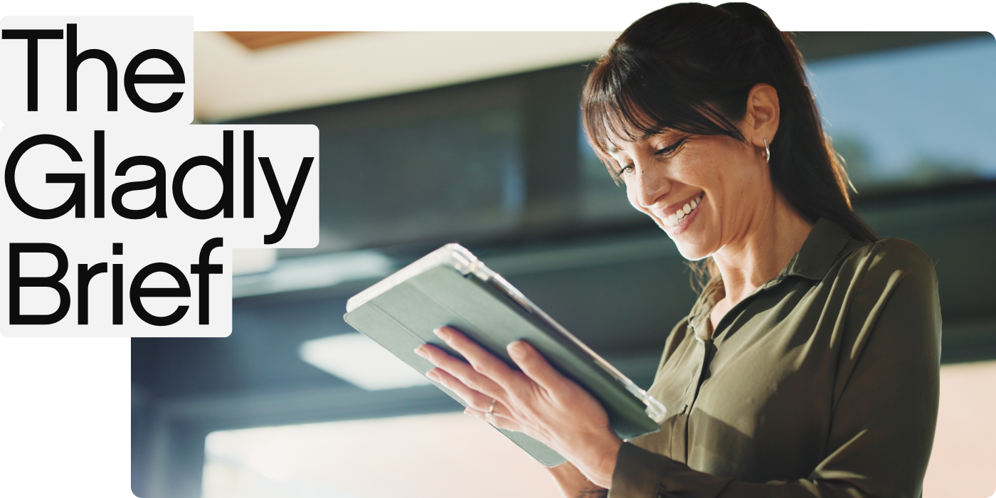 A woman in a green blouse smiles while holding a tablet. Bright indoor setting, with &quot;The Gladly Brief&quot; text overlay in bold black letters on the left.