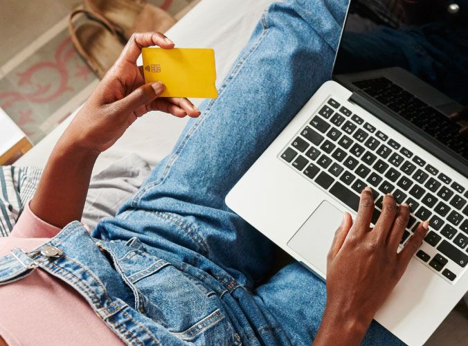Woman looking at credit card to make a purchase on laptop