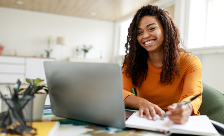 Woman taking notes while using her laptop