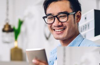 Man with glasses smiling at his smartphone