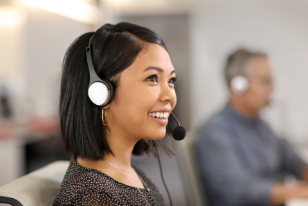 A professional woman with a headset, engaged in a task within an office setting.