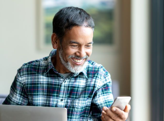 Older man smiling and looking at his cellphone