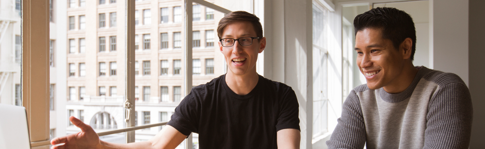 Two men sitting at a desk with an open notebook