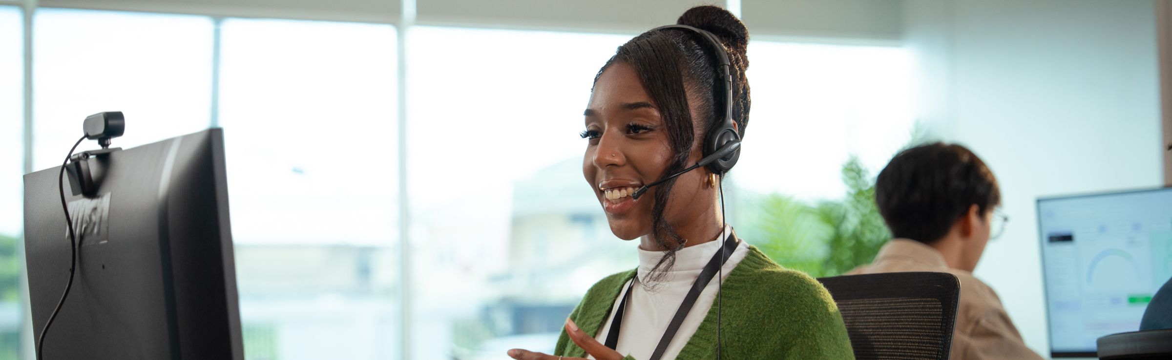 Customer support agent having a conversation on her headset and desktop computer