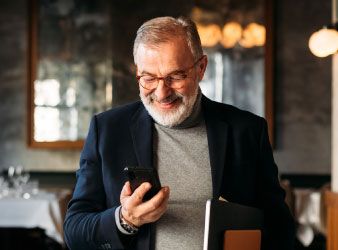 Older gentleman with turtleneck smiling at his phone