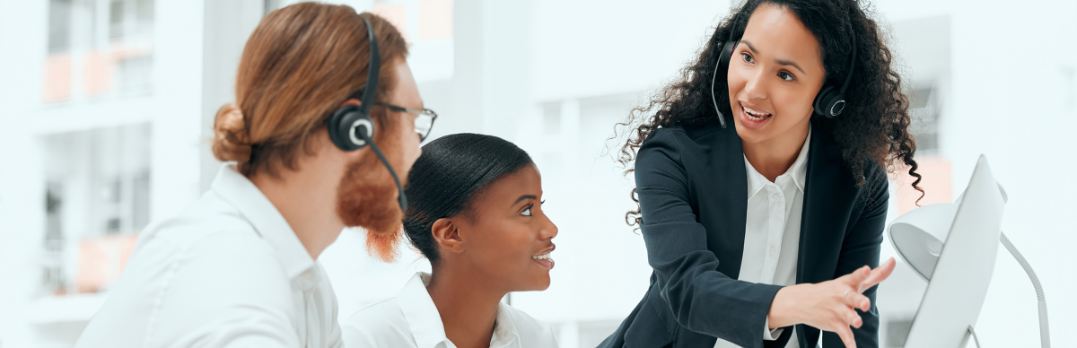 Three customer experience agents reviewing a desktop computer