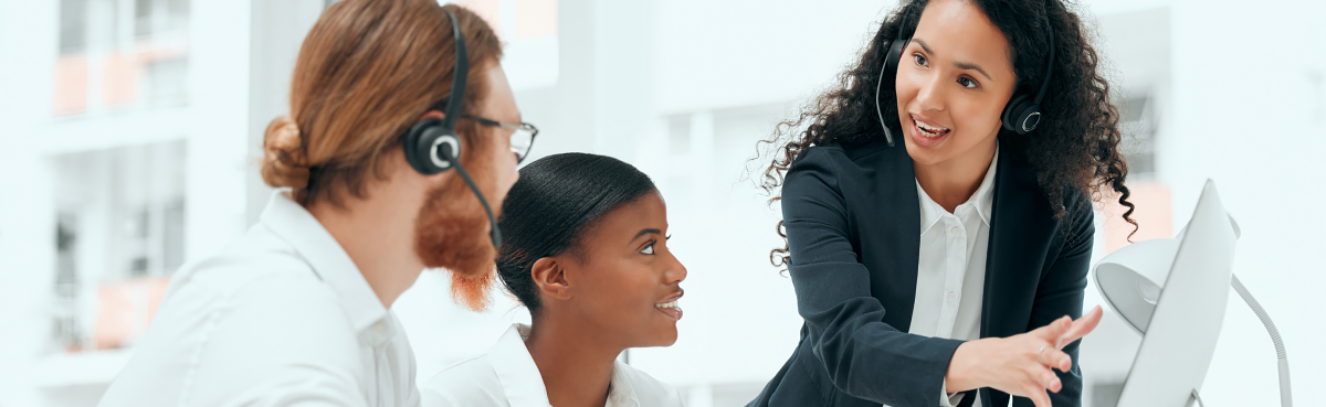 Three customer experience agents reviewing a desktop computer