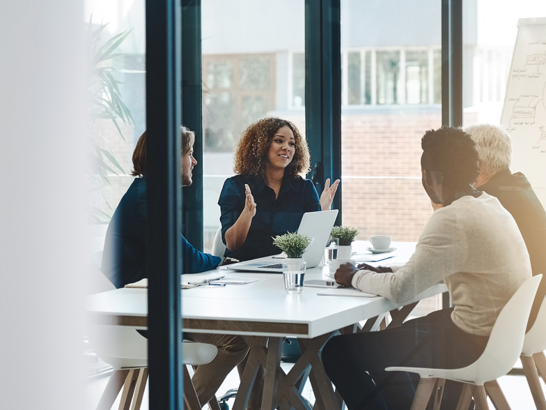 A customer experience leader leads a strategy meeting with her cross-functional team in a modern office