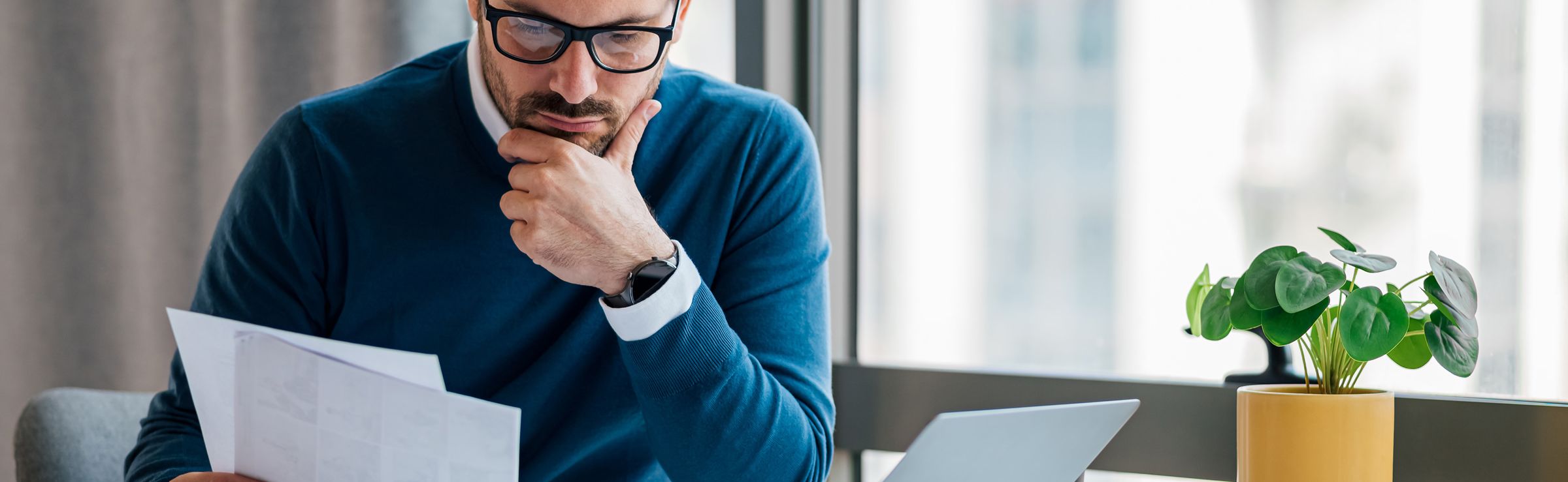 Man reviewing paperwork while sitting with laptop