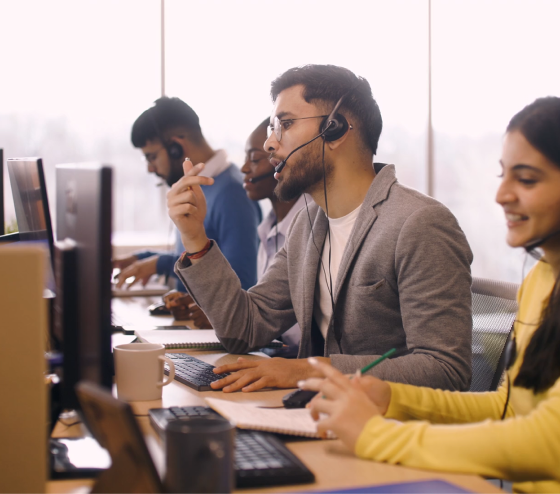 Customer service agents wearing headsets working at computers in an open office.