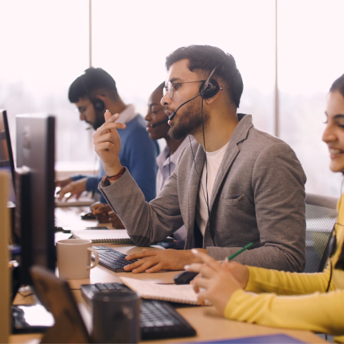 Customer service agents wearing headsets working at computers in an open office.
