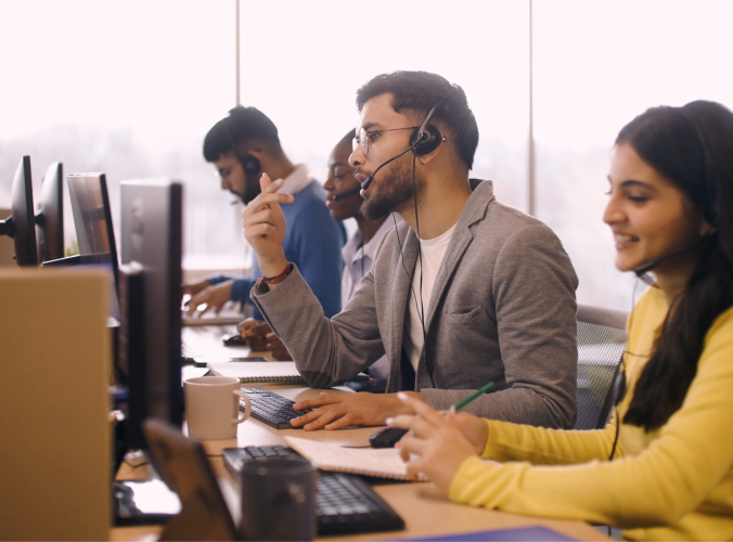 Customer service agents wearing headsets working at computers in an open office.