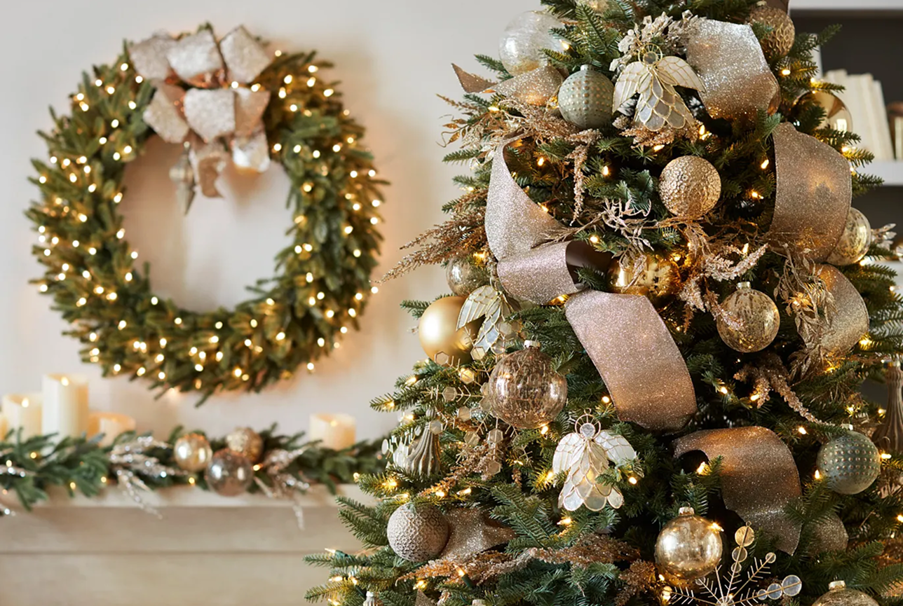 Festive Christmas scene with a decorated tree and wreath. The tree has gold ribbons and ornaments, while soft glowing lights create a warm holiday ambiance.