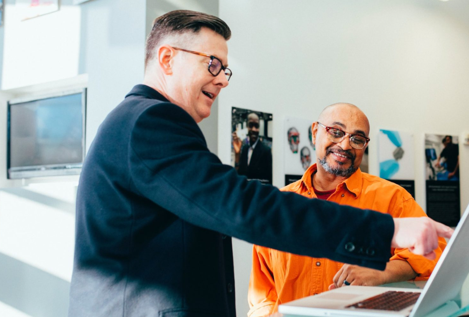 Two men discussing something on a laptop in front of them