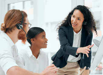 Three customer experience agents reviewing a desktop computer