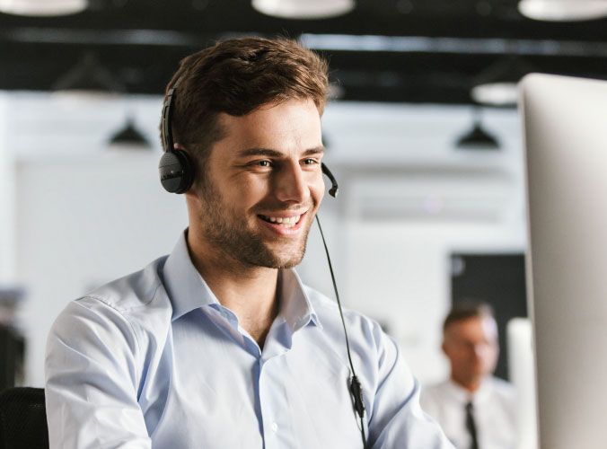 smiling customer service agent with headset on computer